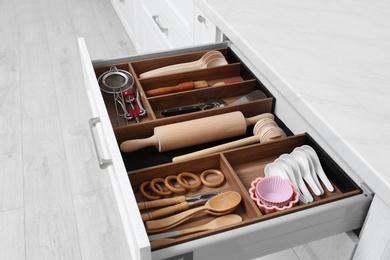 Open drawer with utensil set indoors. Order in kitchen