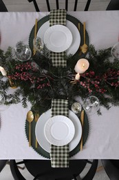 Christmas table setting with festive decor and dishware, top view