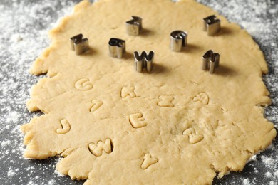 Photo of Making shortcrust pastry. Raw dough and cookie cutters on grey table