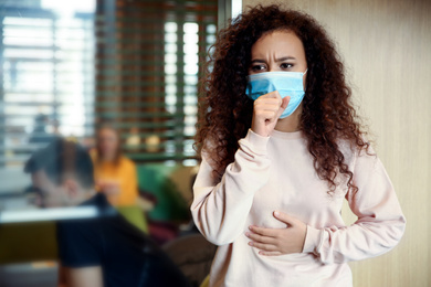 Photo of African-American woman with disposable mask in cafe. Virus protection