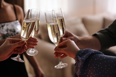 People clinking glasses with champagne at home, closeup