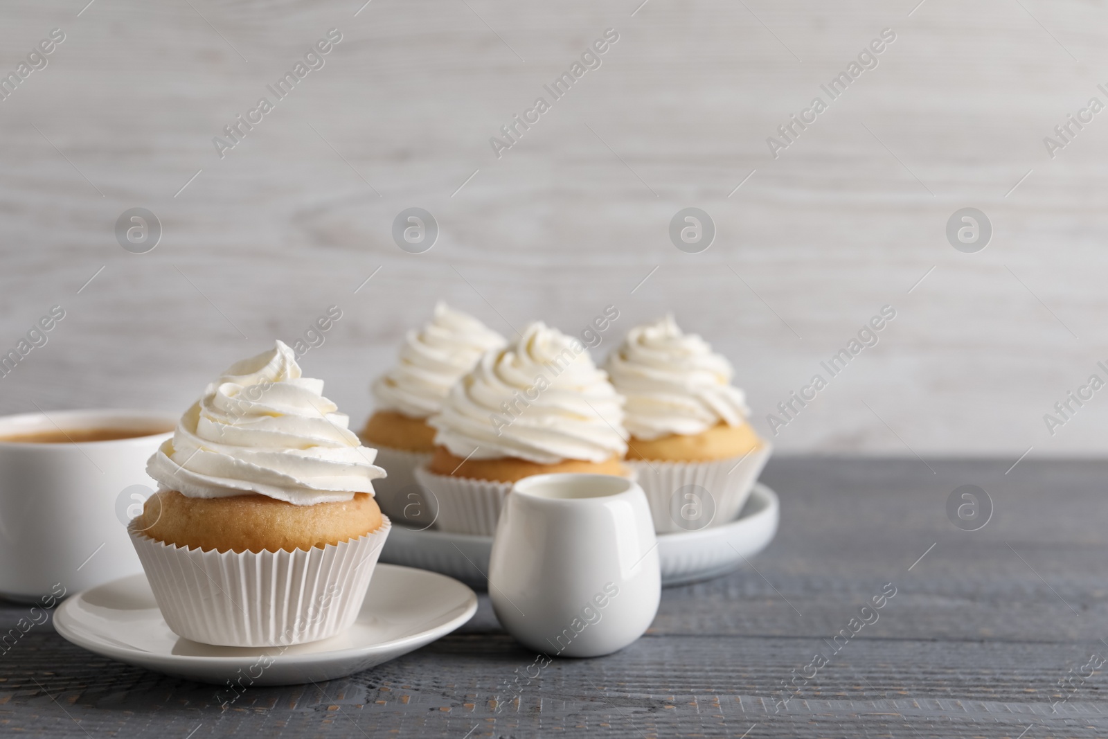 Photo of Delicious cupcakes with cream on grey wooden table. Space for text