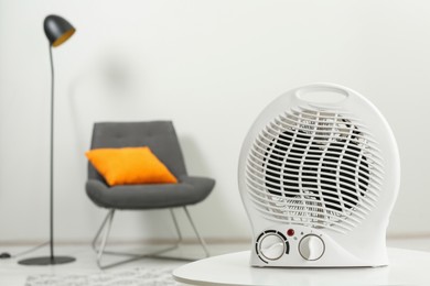 Compact electric fan heater on white table indoors, closeup. Space for text