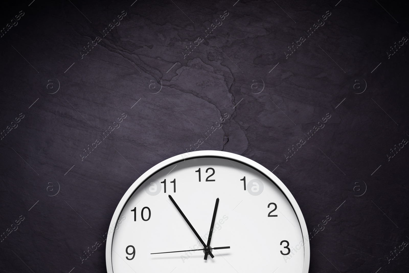 Photo of Stylish round clock on black table, top view with space for text. Interior element