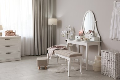 Wooden dressing table with decorative elements and makeup products in room. Interior design