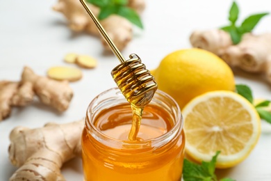 Photo of Honey, ginger and lemon on white table, closeup. Natural cold remedies