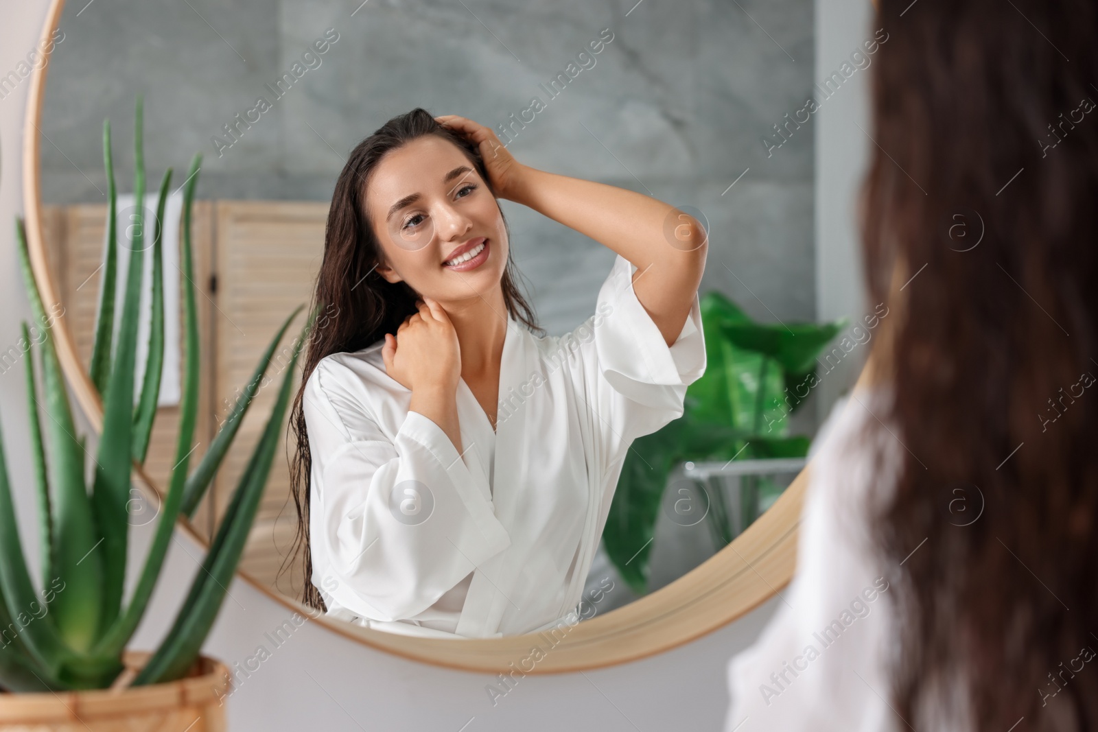 Photo of Beautiful young woman near mirror in bathroom. Hair care