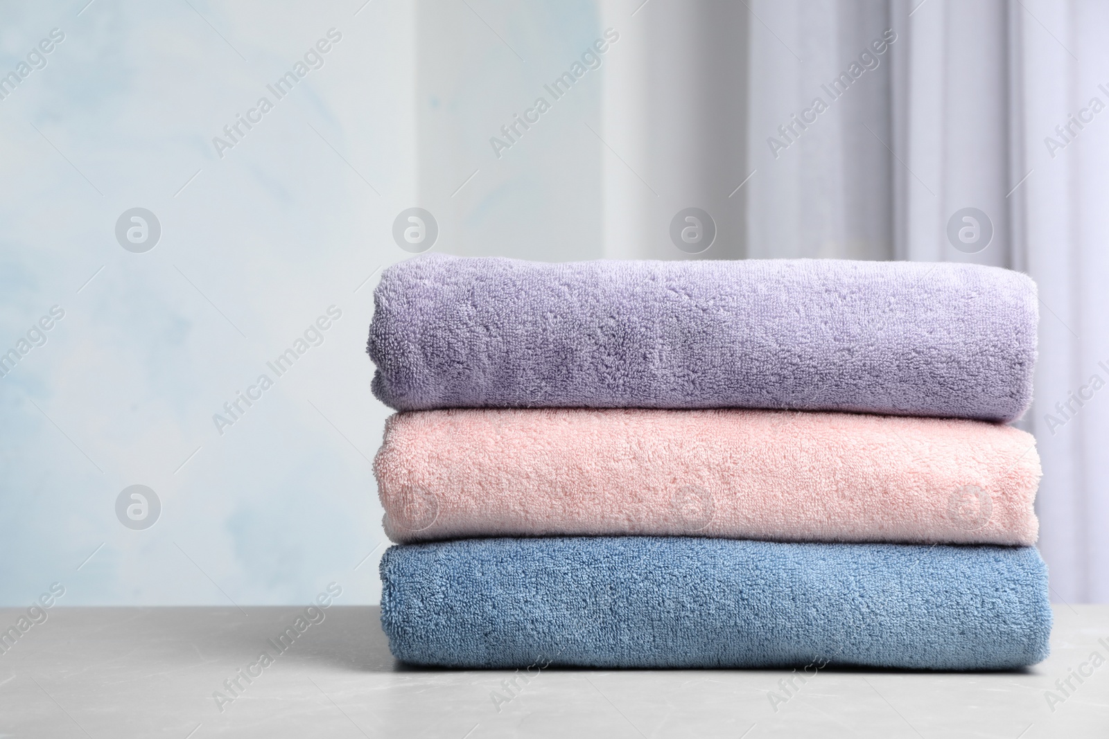 Photo of Stack of soft bath towels on table against blurred background. Space for text