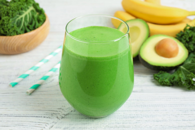 Tasty fresh kale smoothie on white wooden table, closeup