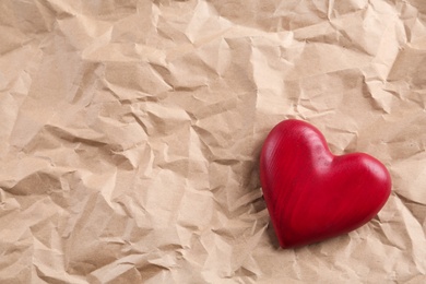 Red wooden heart on crumpled kraft paper, top view with space for text. St. Valentine's day