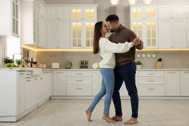 Photo of Affectionate young couple dancing and kissing in kitchen. Space for text