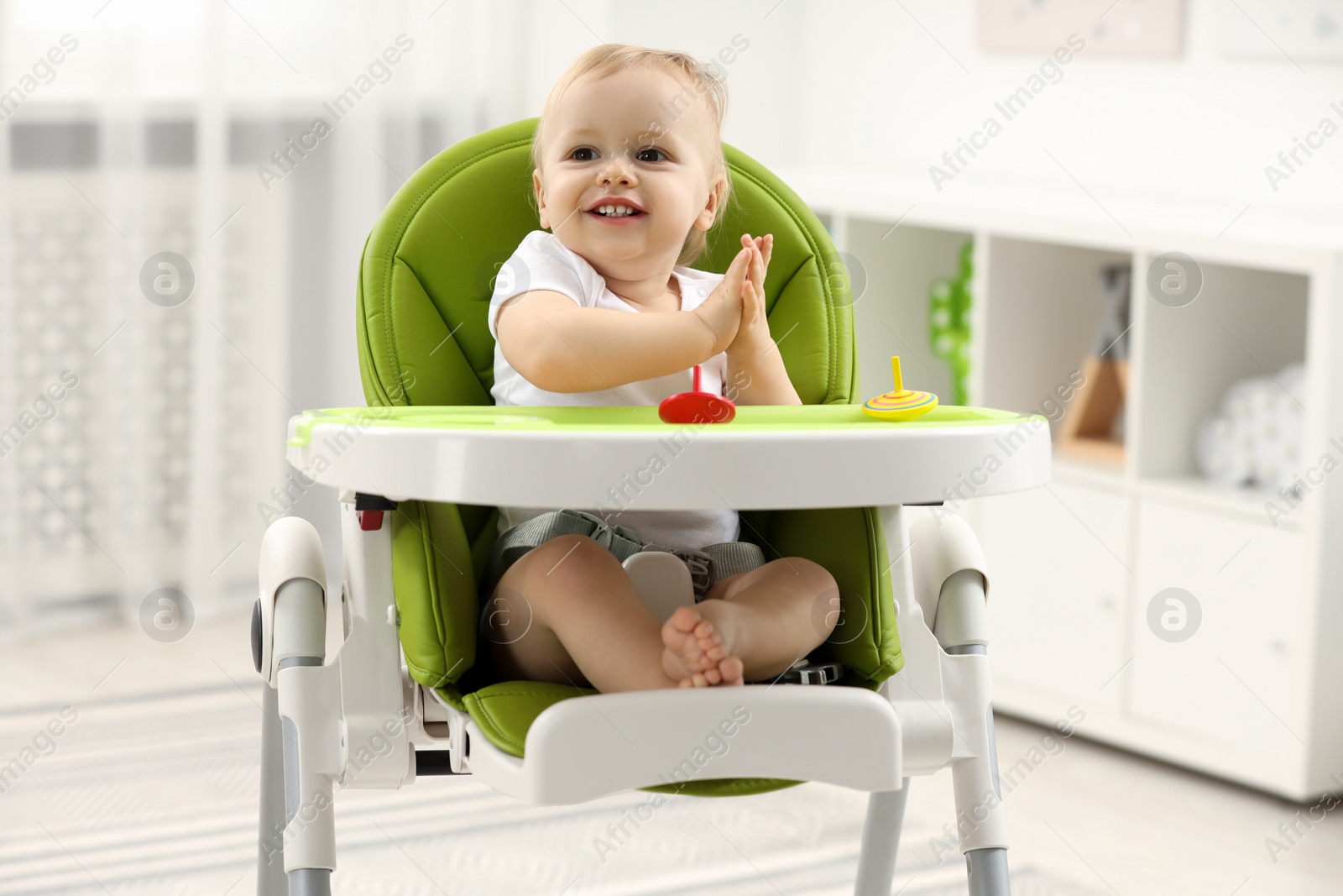 Photo of Children toys. Cute little boy with spinning tops in high chair at home