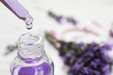 Natural oil dripping into bottle and lavender flowers on table, closeup with space for text. Cosmetic product