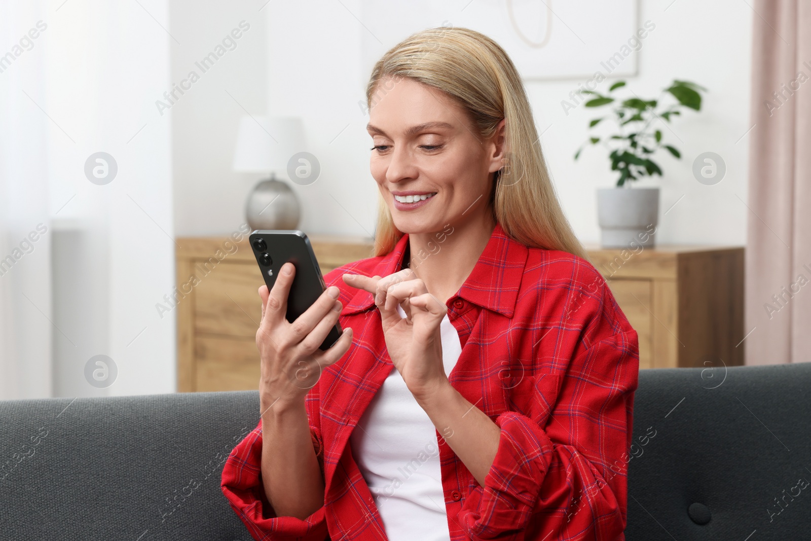 Photo of Woman sending message via smartphone at home