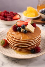 Photo of Delicious pancakes with fresh berries, butter and honey on white marble table, closeup