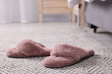 Pink soft slippers on carpet at home, closeup