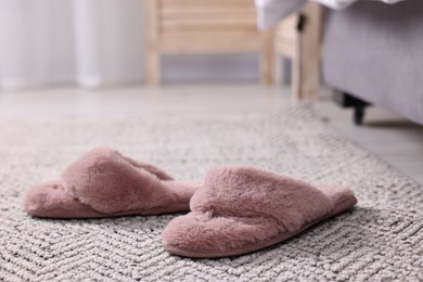 Photo of Pink soft slippers on carpet at home, closeup