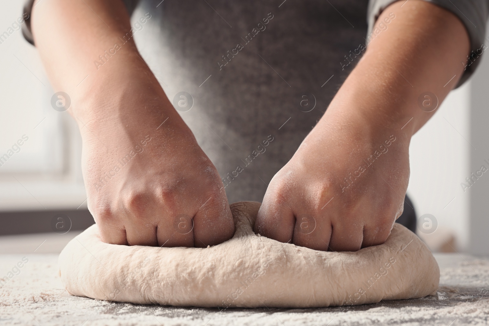 Photo of Man kneading dough at table in kitchen, closeup