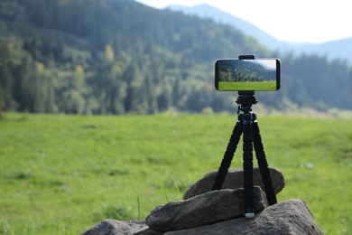 Photo of Taking photo of beautiful mountain landscape with smartphone mounted on tripod outdoors, space for text