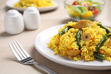 Delicious pilaf with chicken meat on wooden table