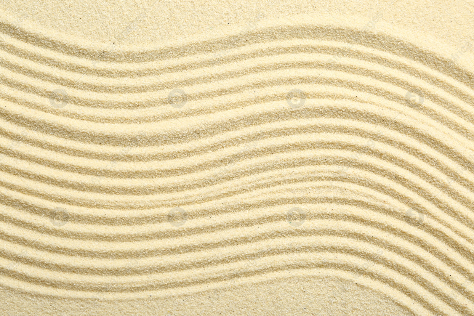 Photo of Zen rock garden. Wave pattern on beige sand, top view