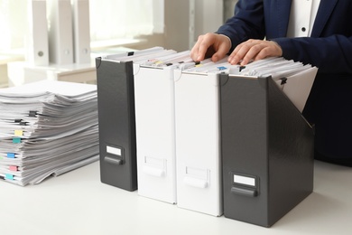 Woman taking documents from folder in archive, closeup