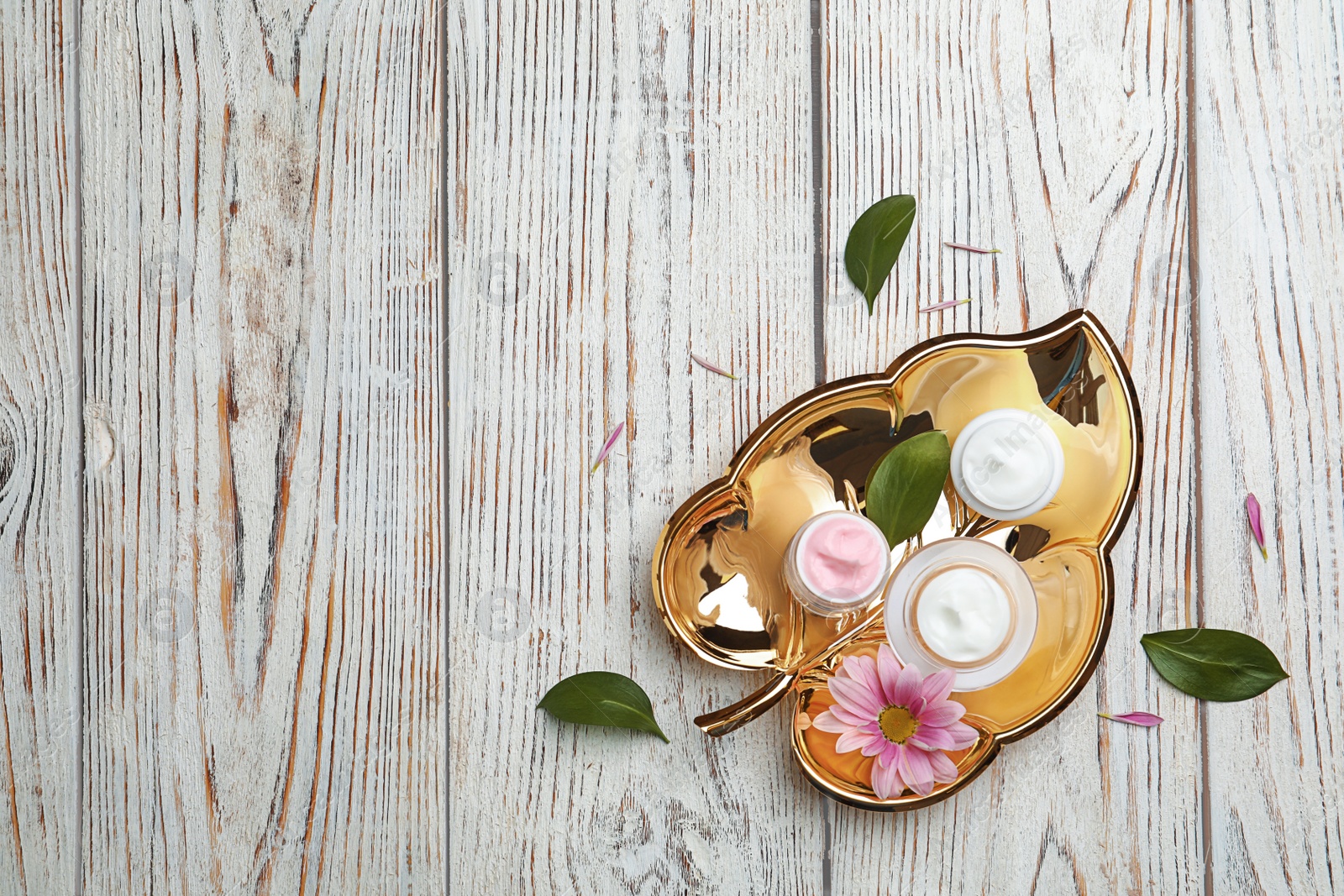 Photo of Composition with body cream in jars on wooden background, top view