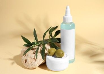 Photo of Cosmetic products and olives on beige background