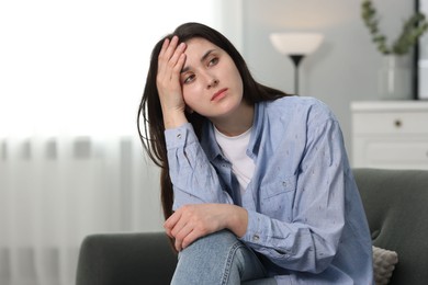 Overwhelmed woman sitting on sofa at home