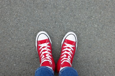 Photo of Woman in stylish gumshoes on asphalt, top view