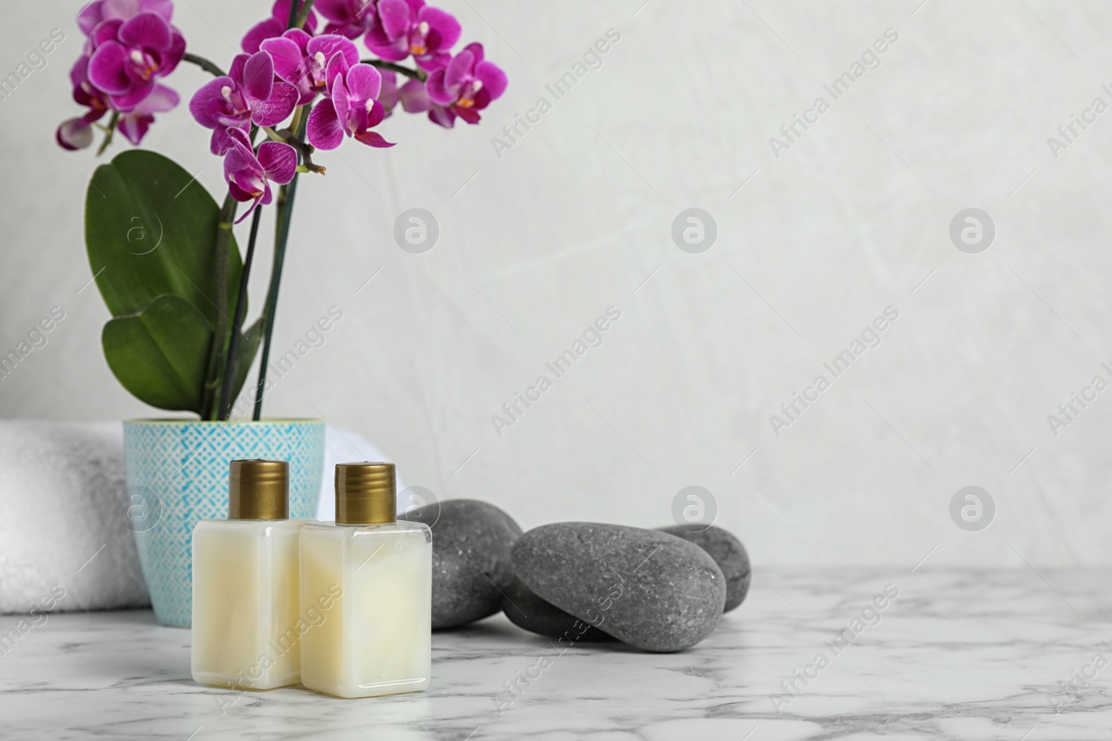 Photo of Spa accessories and blooming orchid on marble table against light background, space for text