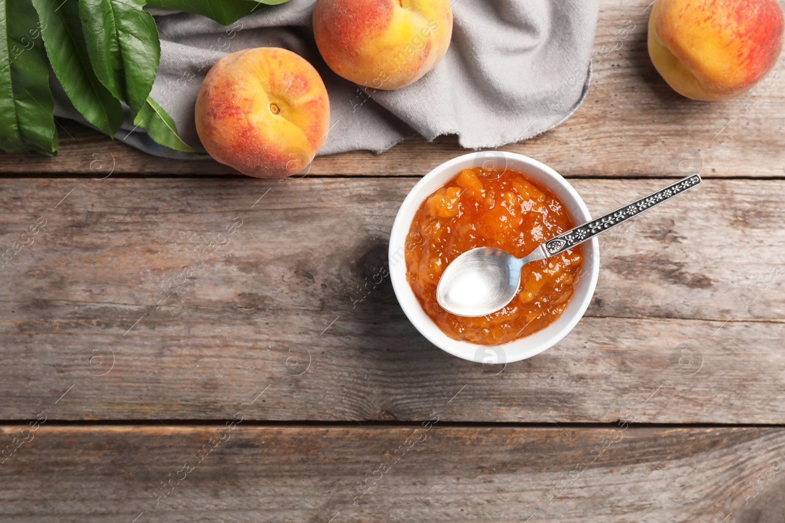 Photo of Flat lay composition with bowl of tasty peach jam, spoon and fresh fruit on wooden table