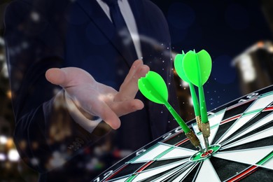 Image of Businessman, darts in board and blurred view of night cityscape