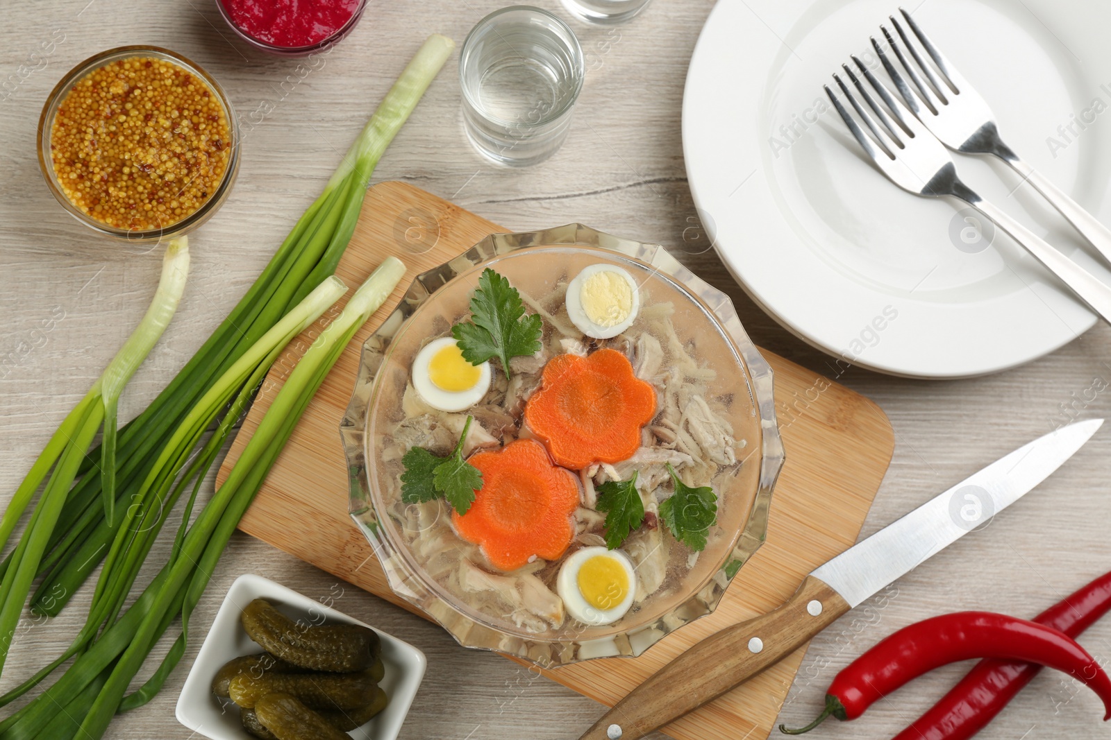 Photo of Delicious aspic with meat and vegetables served on light wooden table, flat lay