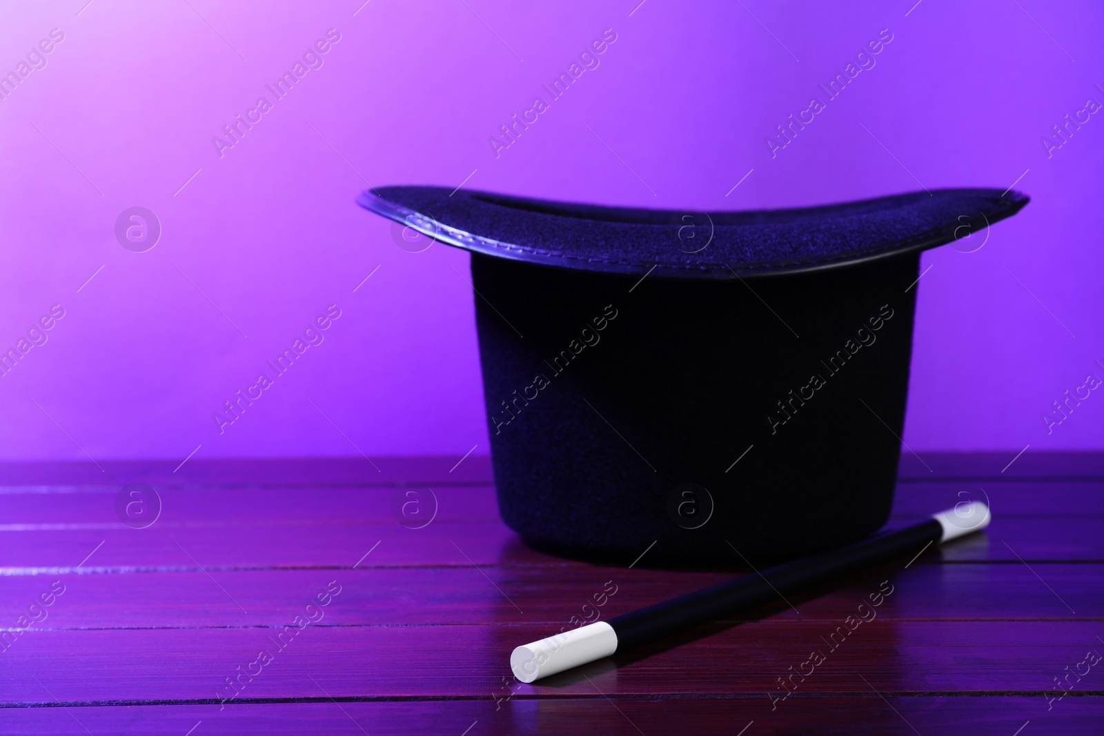 Photo of Black top hat and wand on wooden table, space for text. Magician equipment