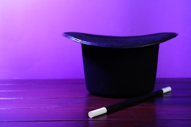 Photo of Black top hat and wand on wooden table, space for text. Magician equipment