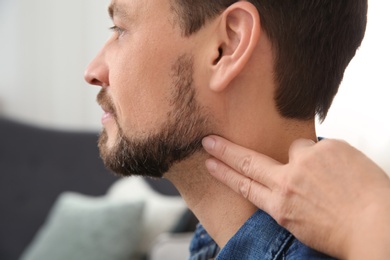 Photo of Mature woman checking man's pulse with fingers indoors, closeup