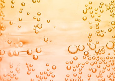 Image of Soda water with bubbles of gas, closeup. Toned in orange
