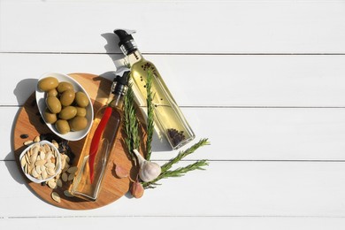 Different cooking oils and ingredients on white wooden table, flat lay. Space for text