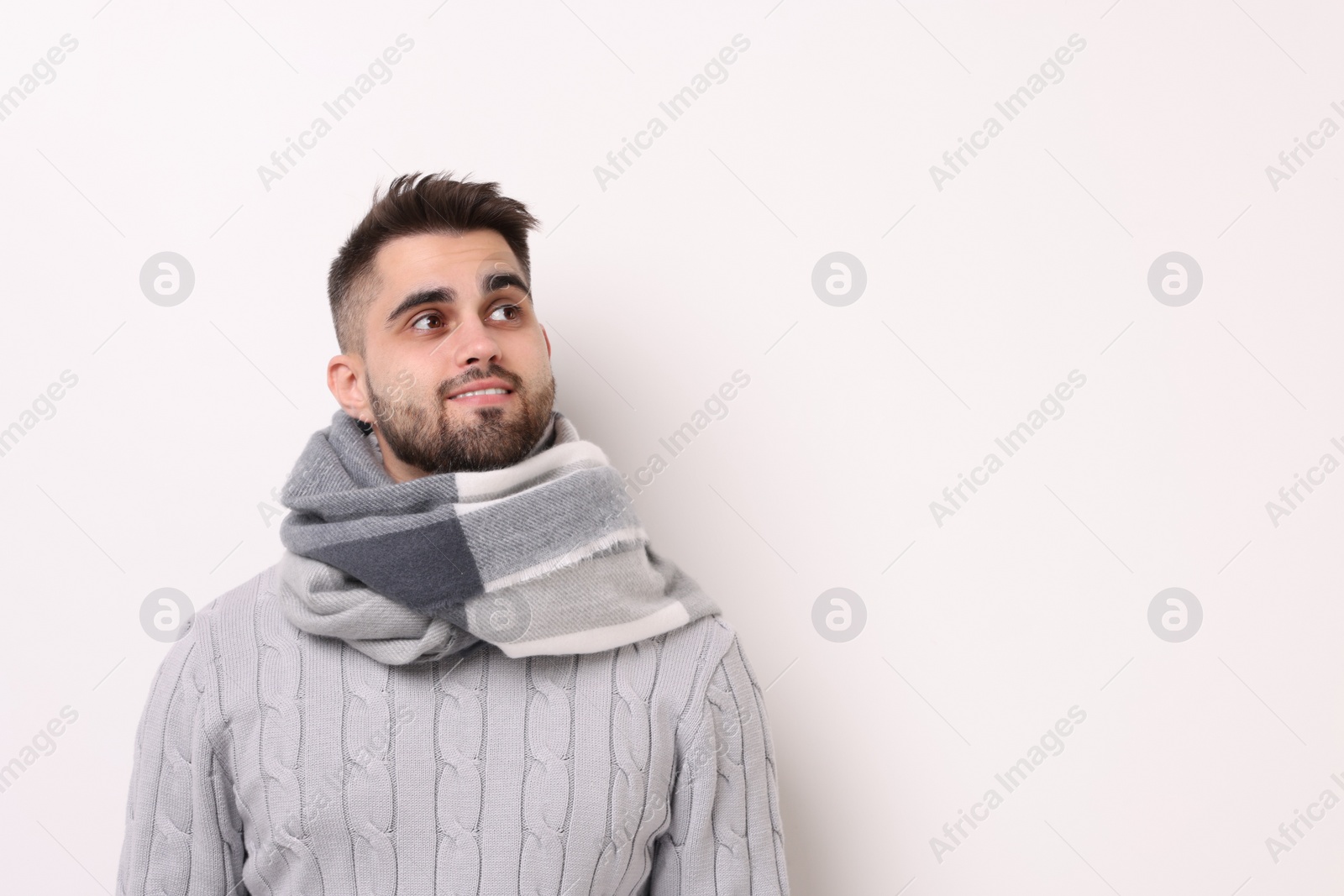 Photo of Portrait of smiling man in warm scarf on light background. Space for text