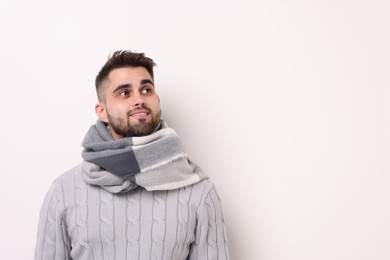 Portrait of smiling man in warm scarf on light background. Space for text