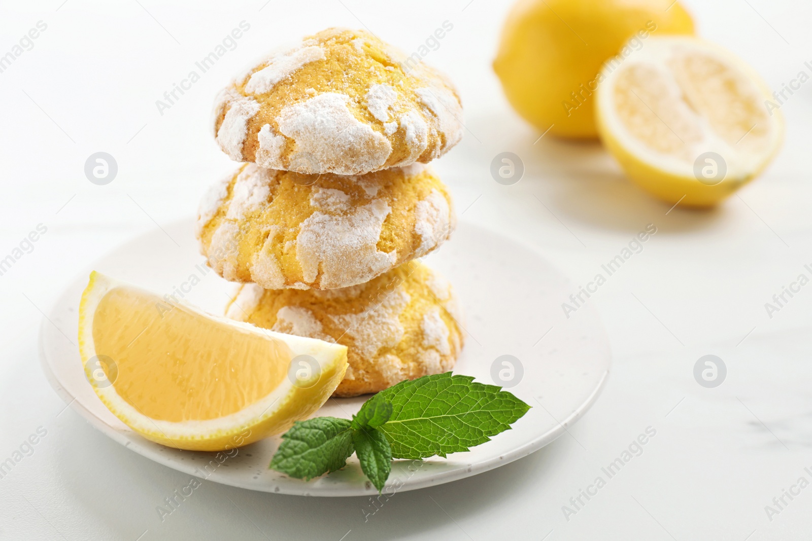 Photo of Tasty homemade lemon cookies with fresh fruit and mint on white marble table