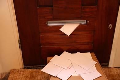 Photo of Wooden door with mail slot, many envelopes and cardboard indoors