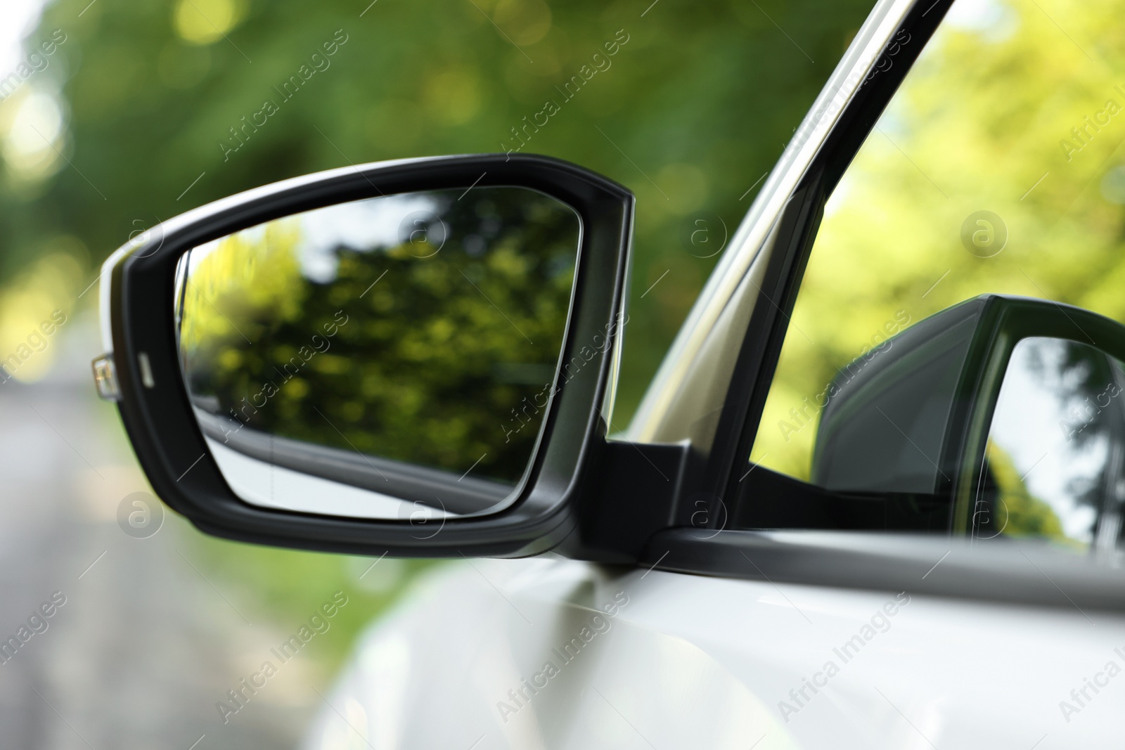 Photo of Side view mirror of modern car on blurred background, closeup