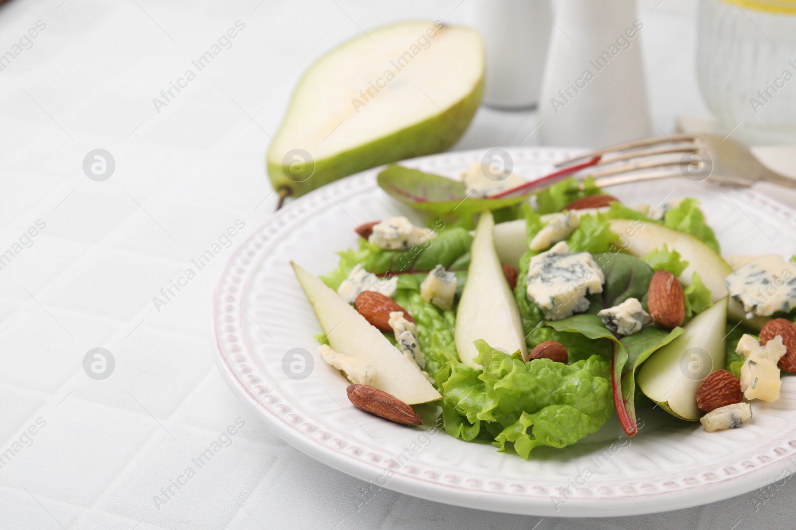 Photo of Delicious pear salad on white tiled table, closeup. Space for text