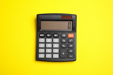 Calculator on yellow background, top view. Office equipment