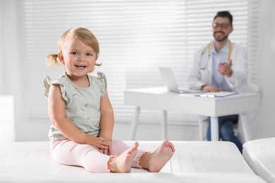 Photo of Pediatrician working at table in clinic, focus on cute little baby