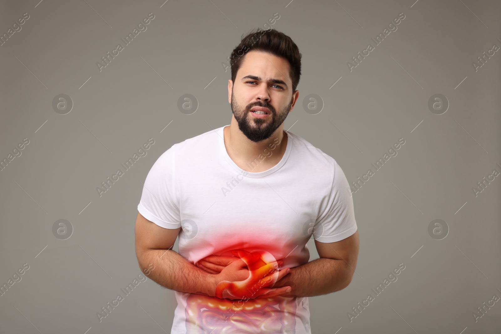 Image of Man suffering from stomach ache on grey background. Illustration of unhealthy gastrointestinal tract