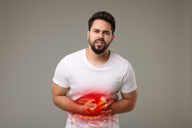 Man suffering from stomach ache on grey background. Illustration of unhealthy gastrointestinal tract