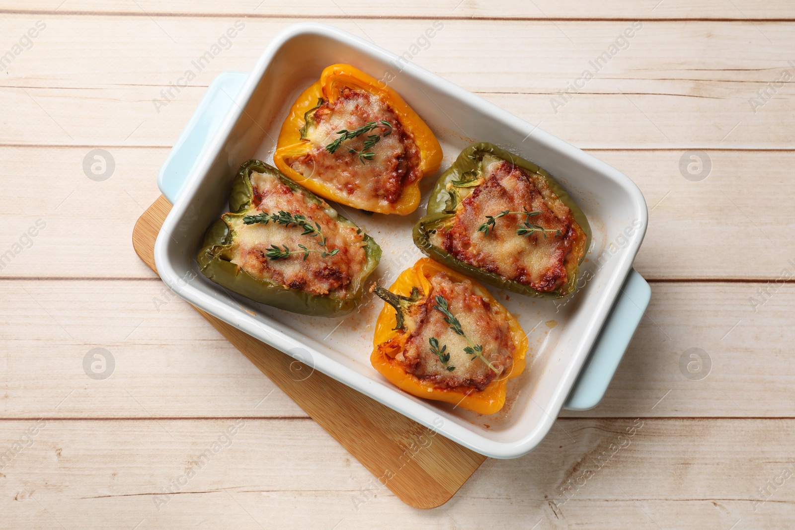 Photo of Tasty stuffed peppers in dish on wooden table, top view